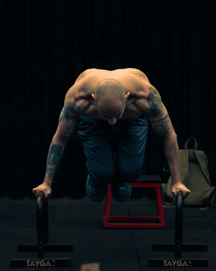 Man holding a tuck planche on parallettes