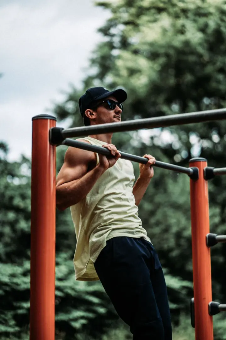 Man at the top of a pull-up on an outdoor bar